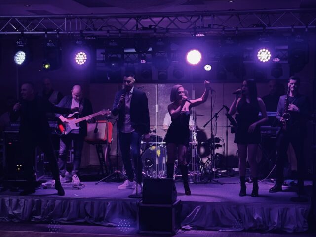 Trupa Atelier cântă live pe scenă la petrecerea corporate ANAT de la Hotel Ramada North București; Sasha în ținută NISSA
